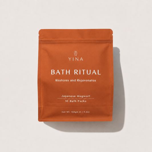 An orange stand-up pouch labeled YINA Bath Ritual, Japanese Mugwort, 10 Bath Packs, photographed on a light neutral background with a soft shadow.